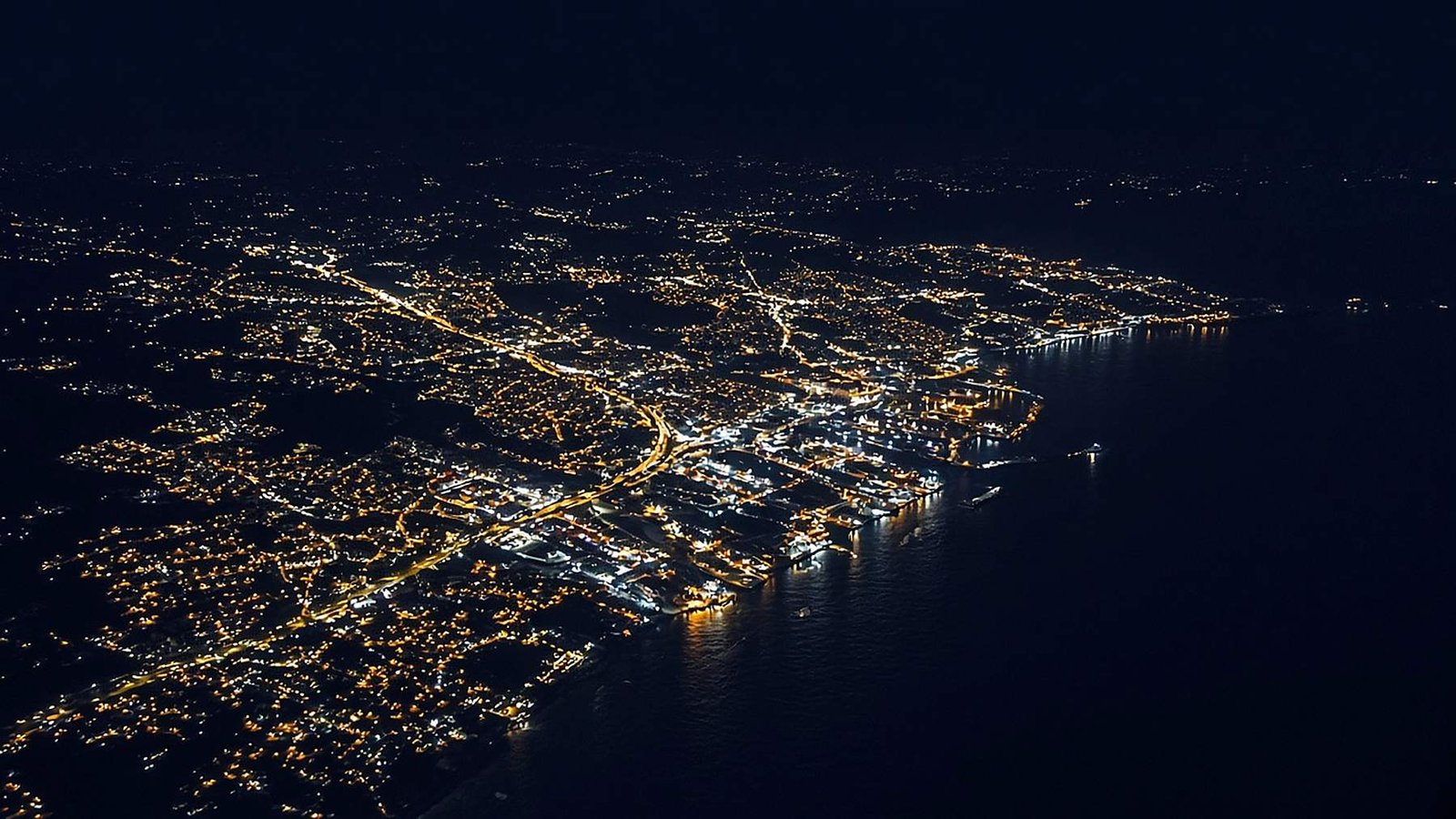 Aerial night view of a lit coastal city, suggesting a connected network of places and partners.