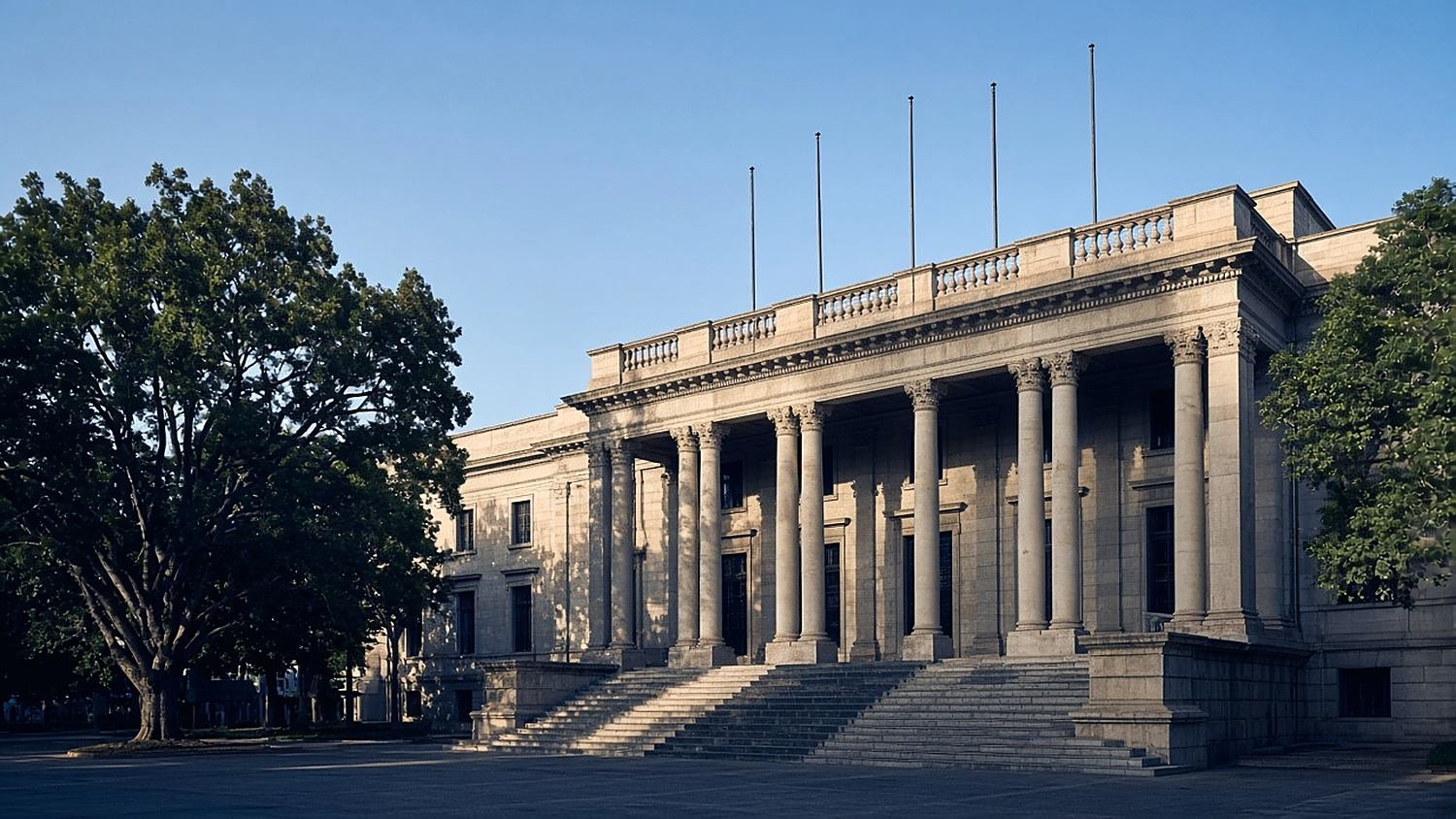Colonnaded government ministry building with a wide flight of steps in late-afternoon sunlight.